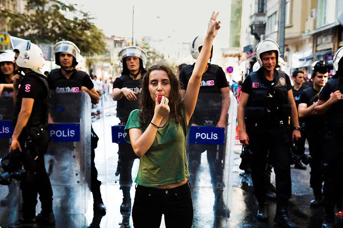 Woman protests with whistle in front of police, highlighting beauty and diversity captured by Romanian photographer.