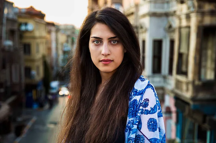 Romanian photographer captures a woman in patterned shawl, showcasing diverse beauty against an urban backdrop.