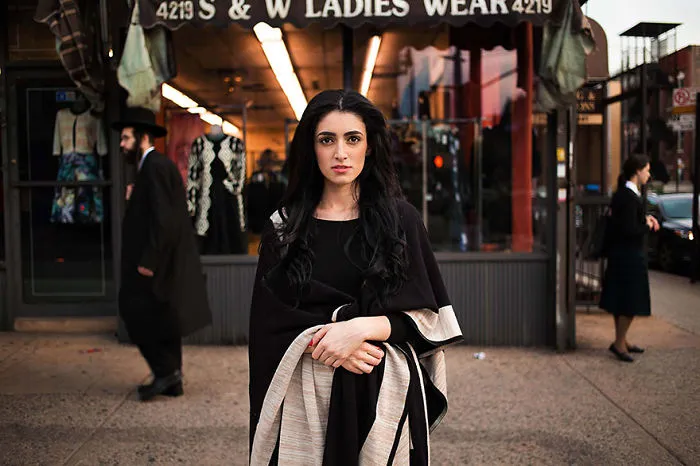 Woman in black dress outside a clothing shop, showcasing diverse beauty, photographed by a Romanian photographer.