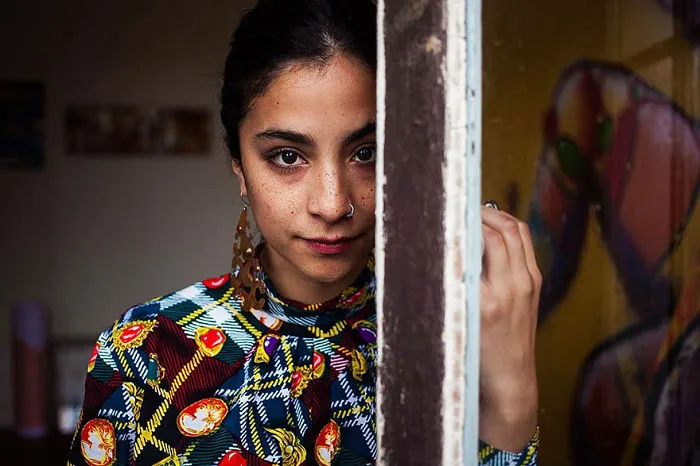 Woman in colorful attire, captured by Romanian photographer, showcasing diverse beauty against a vibrant background.