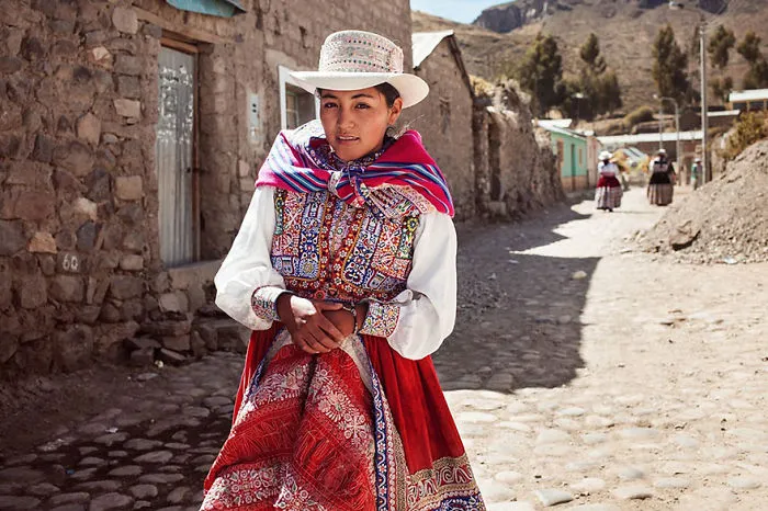 Woman in traditional attire on a cobblestone street, captured by Romanian photographer celebrating beauty worldwide.