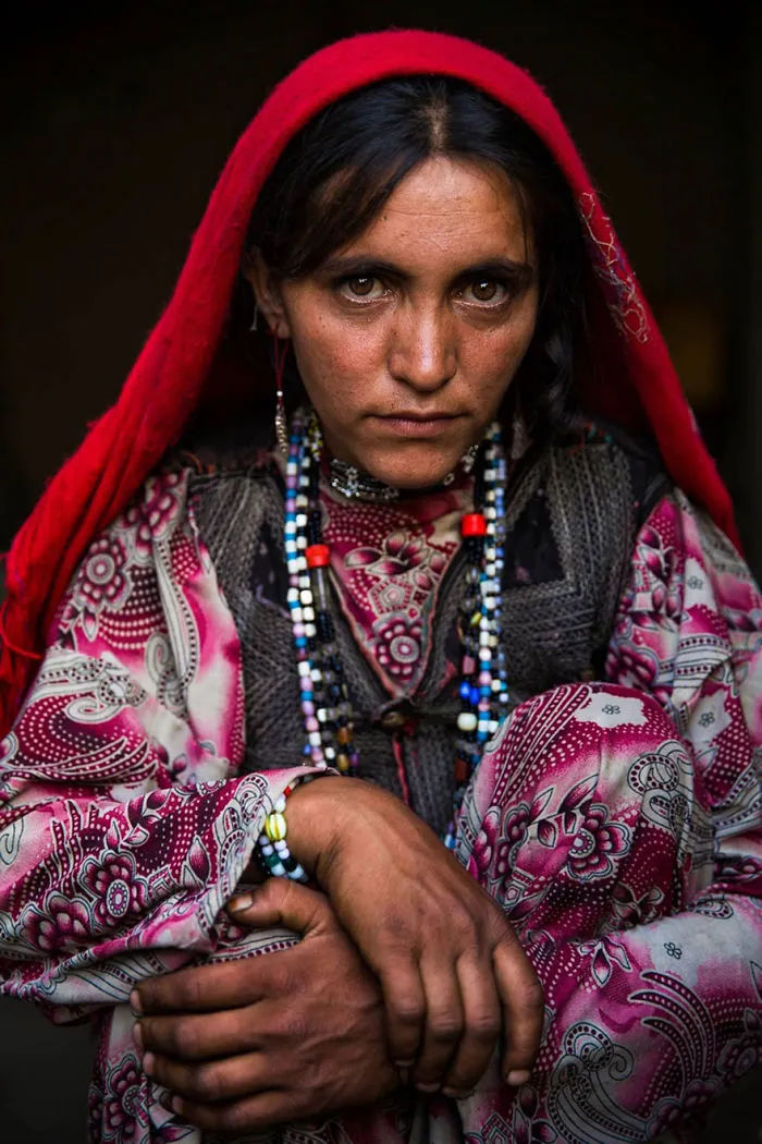 Woman in colorful traditional attire and red headscarf, captured by Romanian photographer showcasing global beauty.