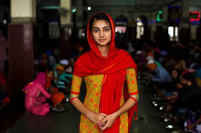 Woman in a colorful scarf, photographed by a Romanian photographer, stands in a vibrant indoor setting showcasing global beauty.