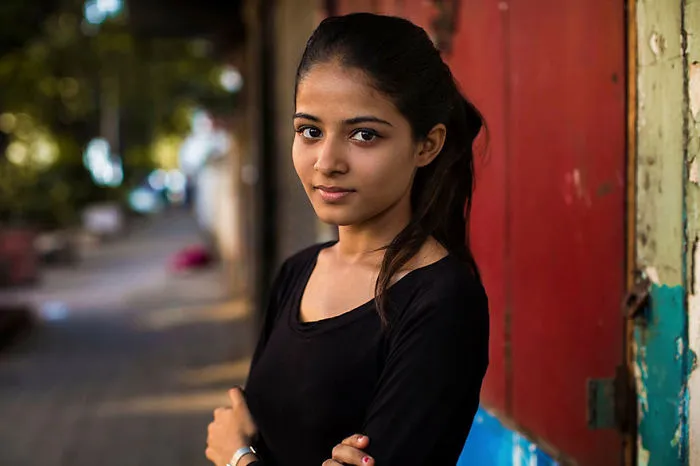 Romanian photographer captures a woman in a black shirt, showcasing diverse beauty against a vibrant urban backdrop.