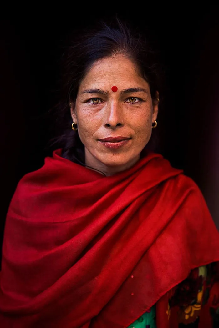 Romanian photographer captures woman in red shawl, showcasing global beauty through diverse portraits from 121 countries.