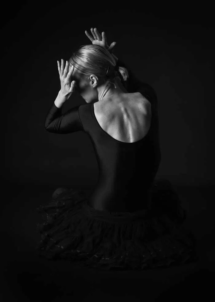 Ballet dancer in a black tutu posing gracefully in dramatic lighting, highlighting the art of ballet.