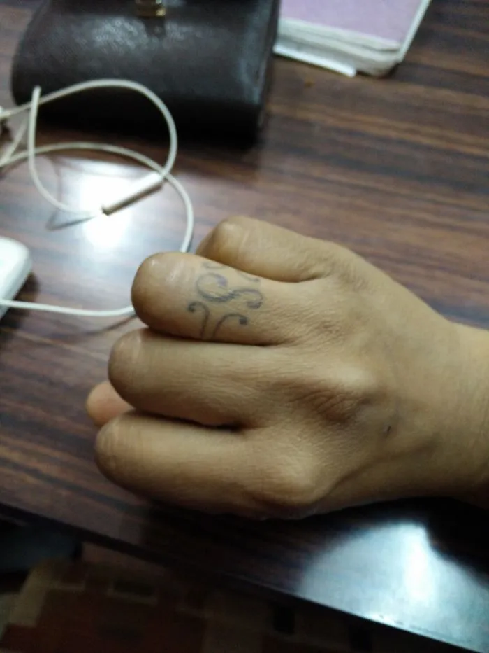 Minimalist tattoo on a person's finger featuring a delicate design.