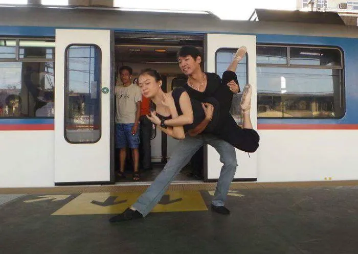 Two ballet dancers performing an elegant pose on a train platform, capturing the essence of dance celebration.