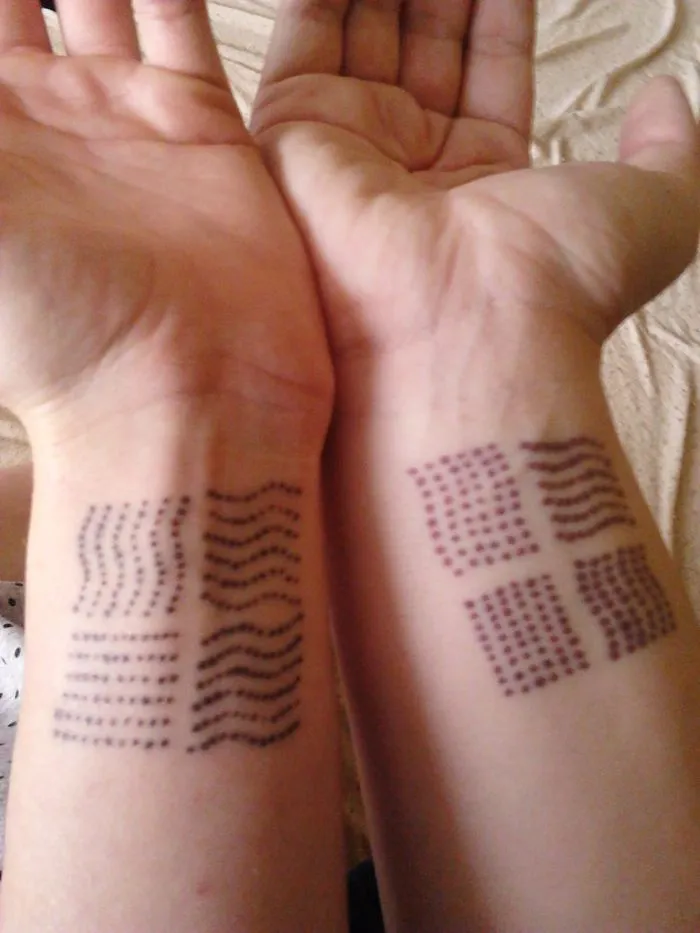 Matching geometric sister tattoos on wrists showing a special bond.