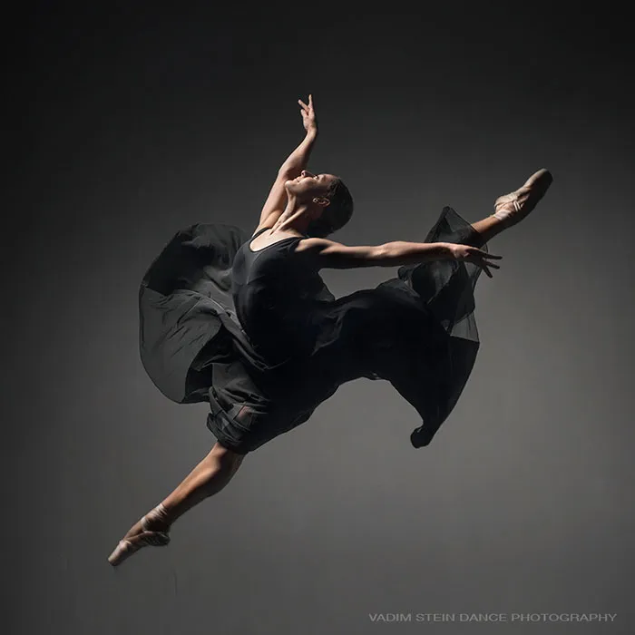 Ballet dancer in a graceful leap wearing a black costume, showcasing the art, elegance, and discipline of ballet.