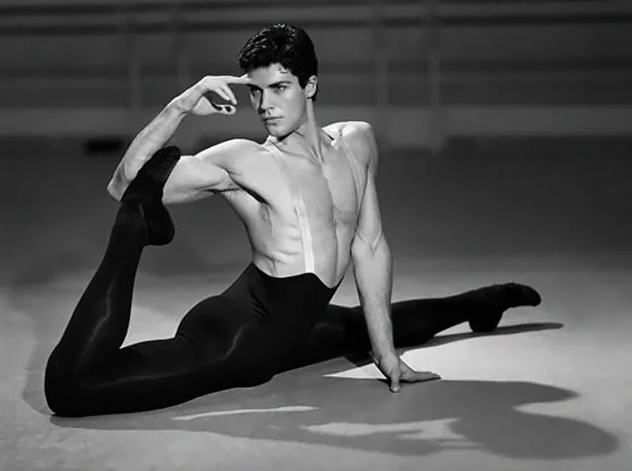 Ballet dancer performing a complex pose, demonstrating strength and flexibility in a dance studio.