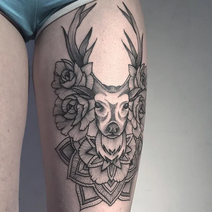 Tattoo of an eerie creature with antlers and floral elements by a Russian artist on a person's thigh.