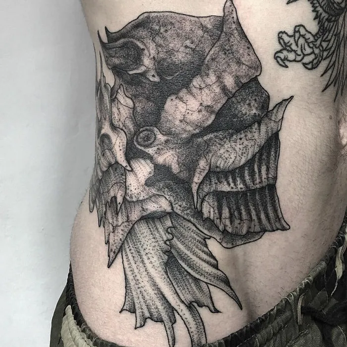 Dark and eerie creature tattoo on skin by Russian artist, showcasing intricate design details and shading.