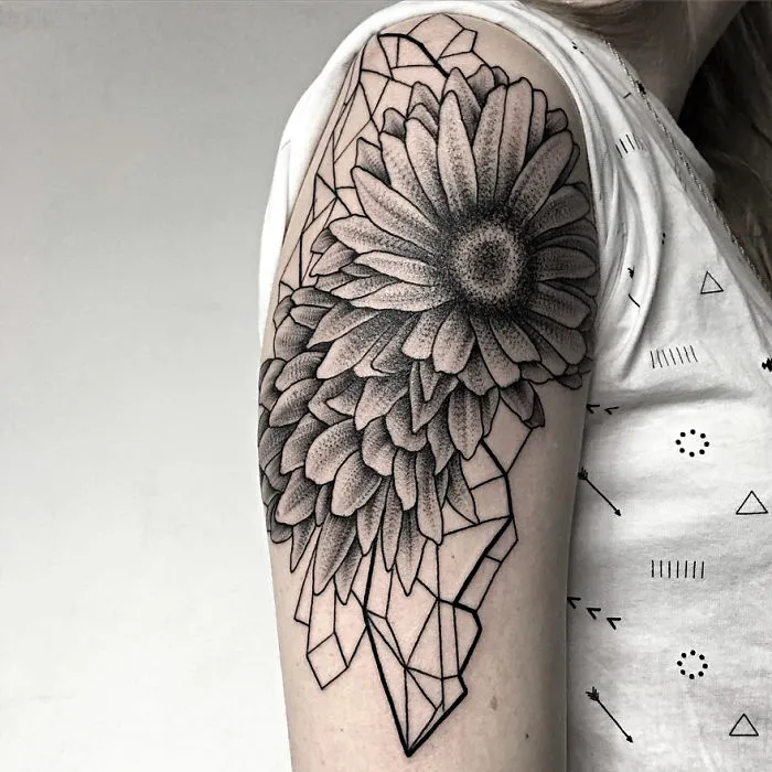 Tattoo of a sunflower and geometric shapes on an upper arm, created by a Russian artist.