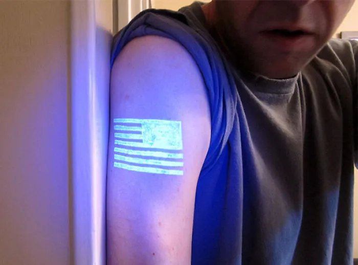 Glow in the dark tattoo of stripes on an arm, visible under black light.