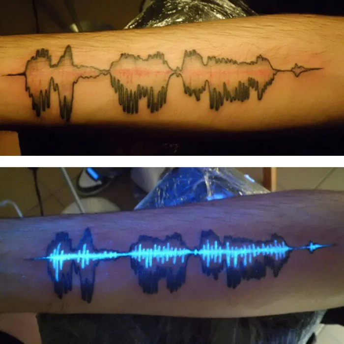 Glow in the dark tattoo of sound waves, visible under black light on an arm.