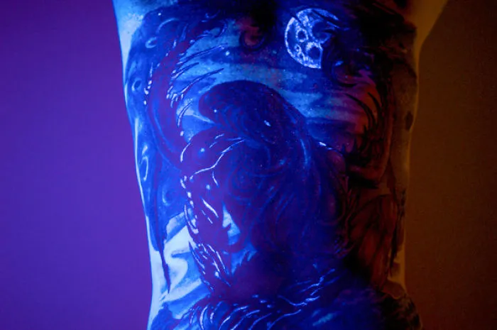 Glow in the dark tattoo of a celestial scene, vividly visible under black light.