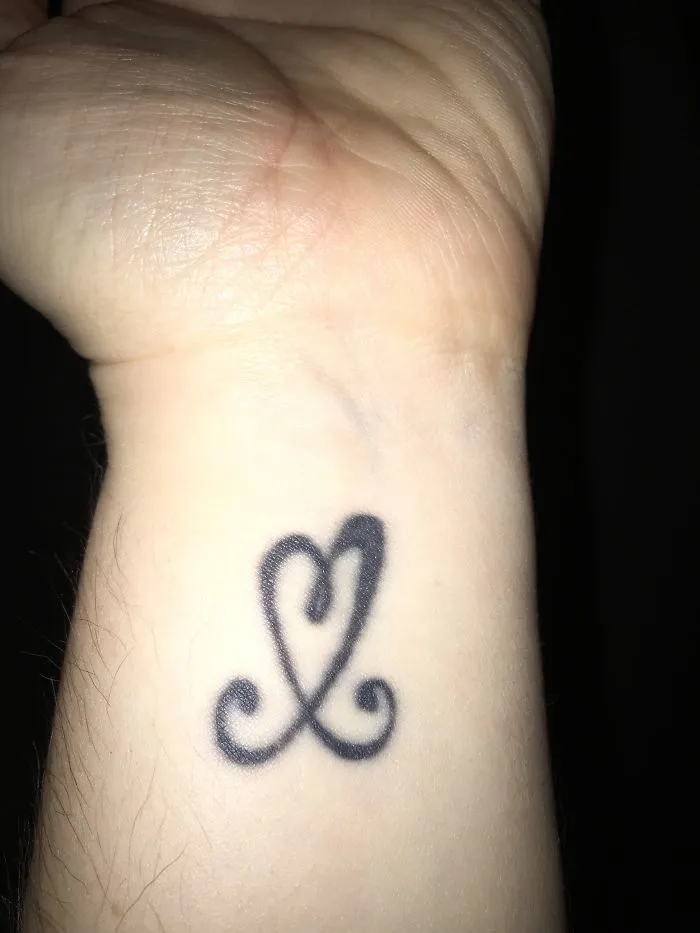 Minimalist tattoo of a stylized heart on a wrist.