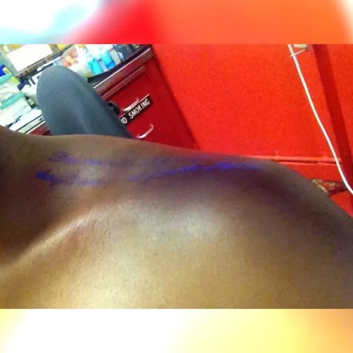 Glow in the dark tattoo on shoulder, illuminated under black light in a tattoo studio.