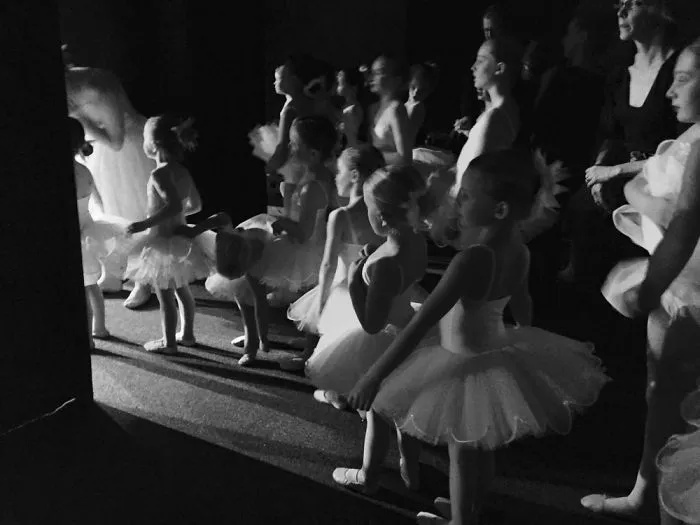 Young ballerinas backstage, preparing in tutus for a performance, capturing the essence of ballet celebration.