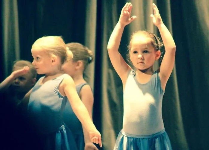 Children in blue dresses practicing ballet, celebrating Ballet Day with graceful poses.