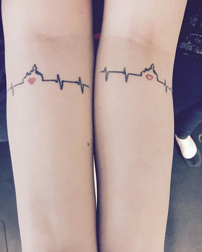 Sister tattoo featuring matching heart and heartbeat design on forearms.