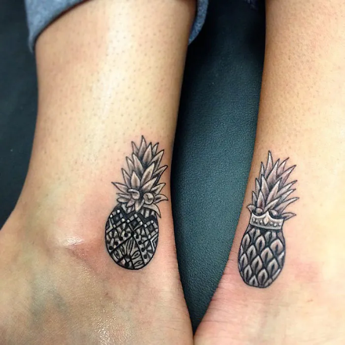 Matching pineapple sister tattoos on ankles, illustrating a unique bond and creative design.