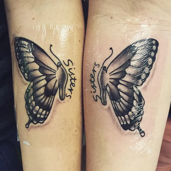 Butterfly tattoos on two arms with the word "Sisters," symbolizing sister bond.