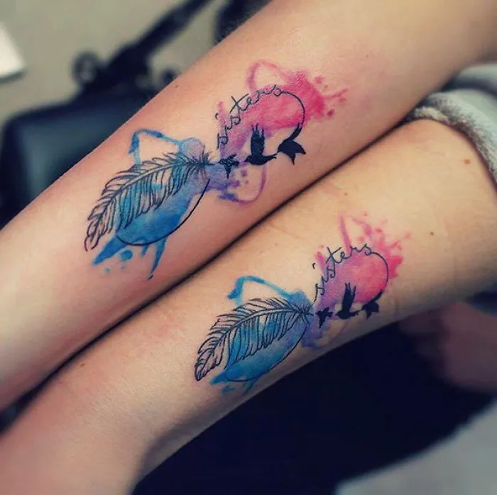 Colorful sister tattoos with feathers and birds on forearms, symbolizing a strong sibling bond.