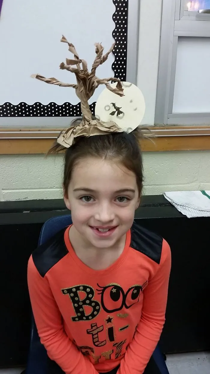 Child with crazy hair day style featuring a spooky tree and moon, wearing a Halloween-themed shirt.