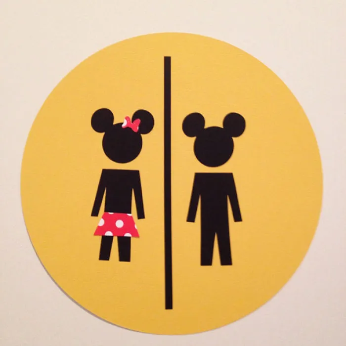 Funny bathroom sign with mouse-eared male and female figures on a yellow background.