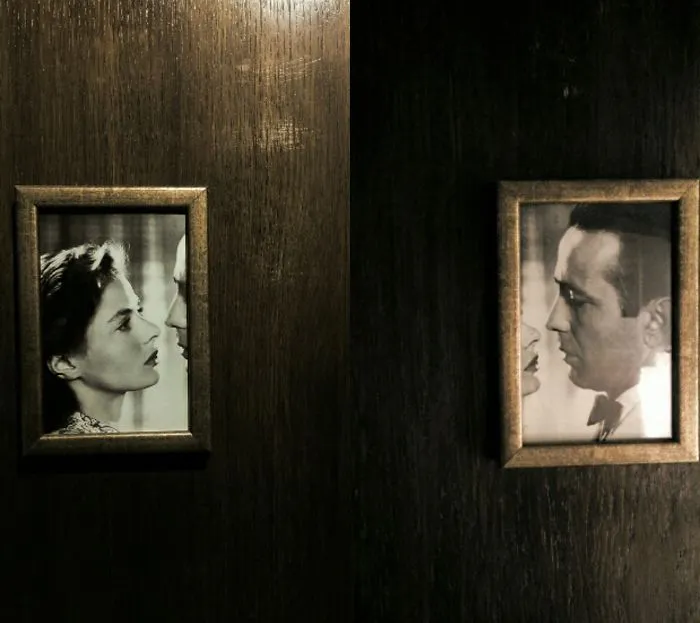 Funny bathroom signs featuring a classic movie couple in black-and-white frames on wooden doors.