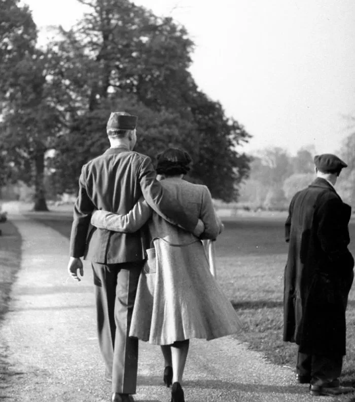 Couple walking arm in arm during wartime, showcasing love amidst conflict in a historic photo.