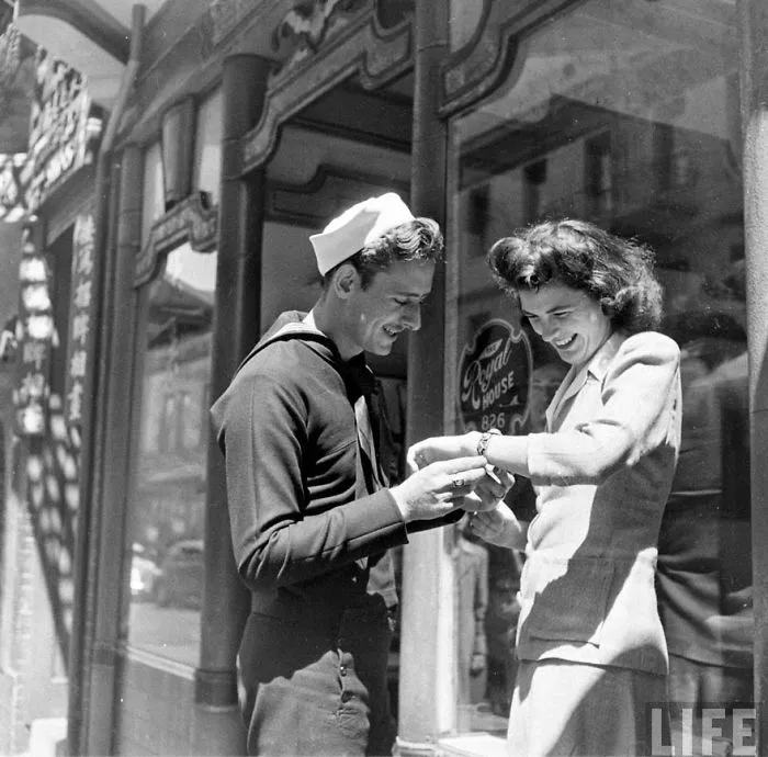 Sailor and woman during wartime, sharing a loving moment on a sunny street, representing historic love in war.
