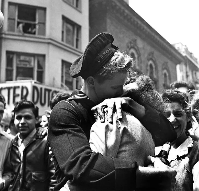 Sailor passionately kissing a woman in a busy street, symbolizing love during wartime.