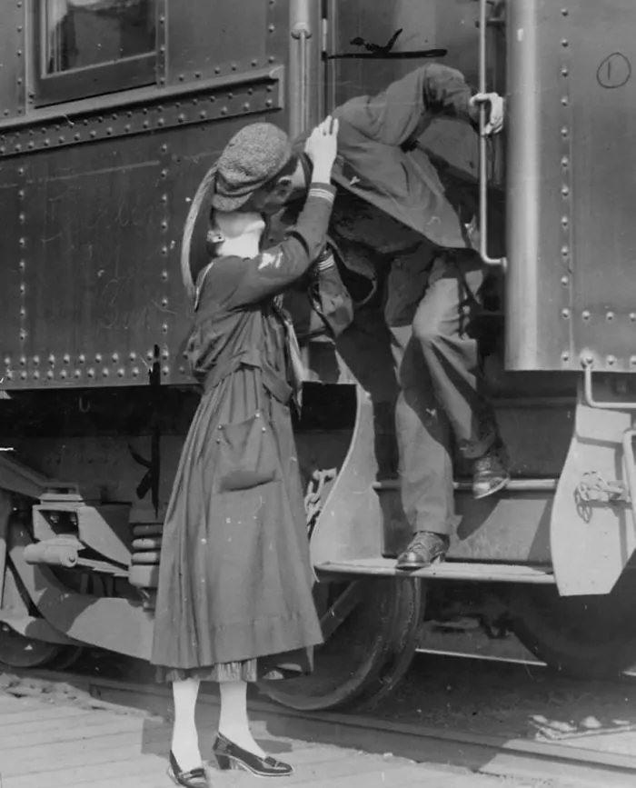 Historic photo of a couple kissing goodbye at a train during wartime, showing love and emotion.