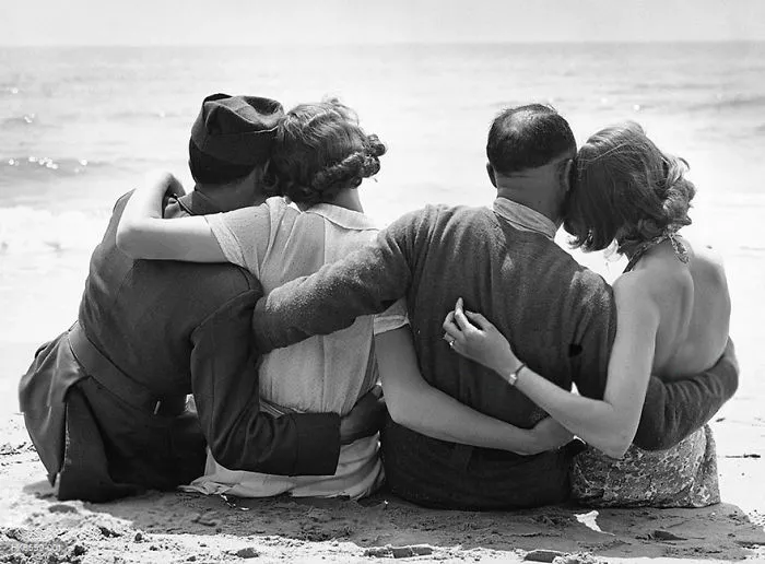 Couples embracing on a beach, showcasing historic love during wartime.
