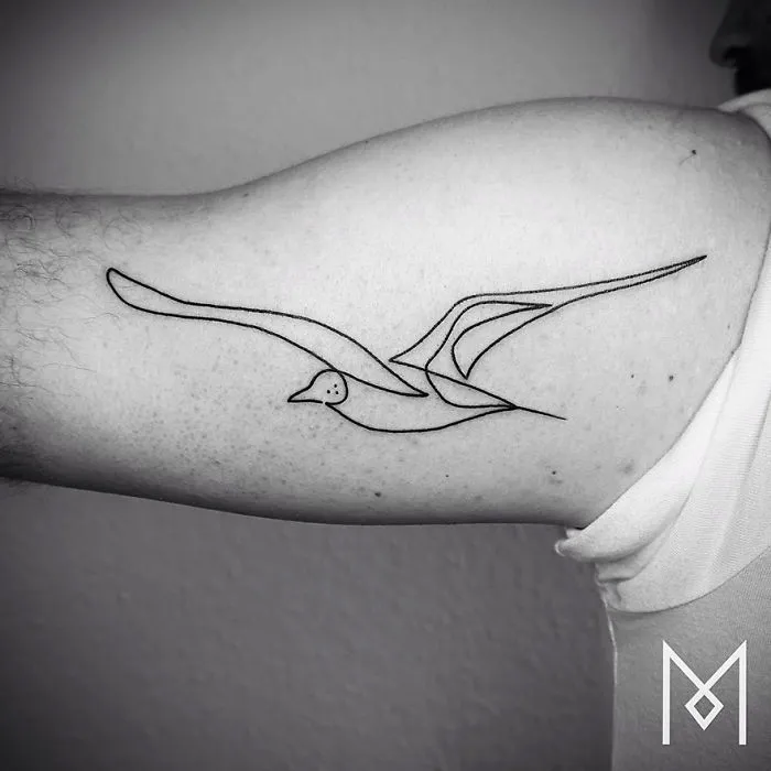 Minimalist single line tattoo of a bird on an arm by Iranian-German artist.