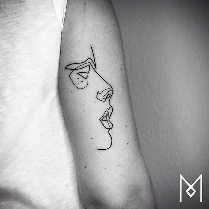 Minimalist single line tattoo of a face on an arm, created by an Iranian-German artist.