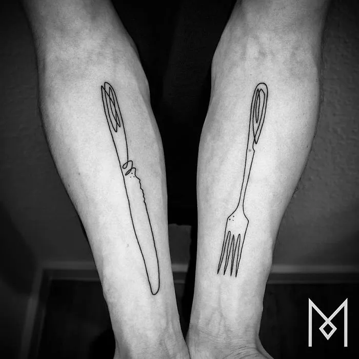 Minimalist single line tattoos of a knife and fork on forearms by Iranian-German artist.