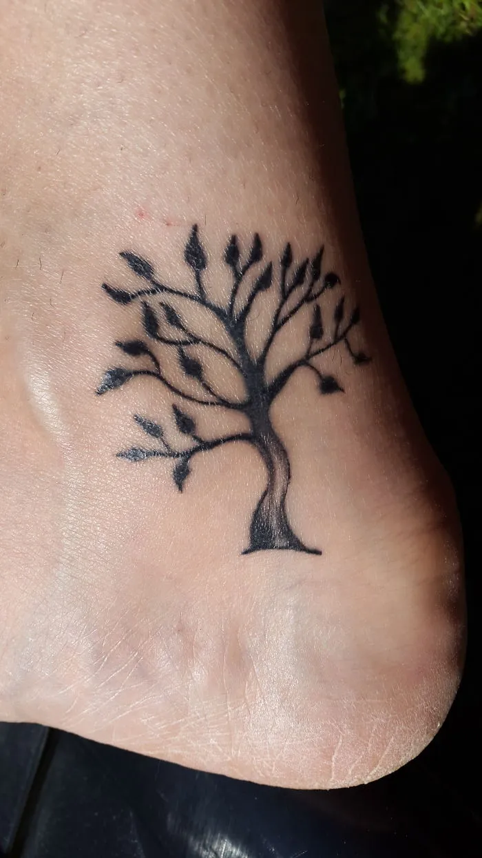 Small foot tattoo of a tree with branches, illustrating minimalist design.
