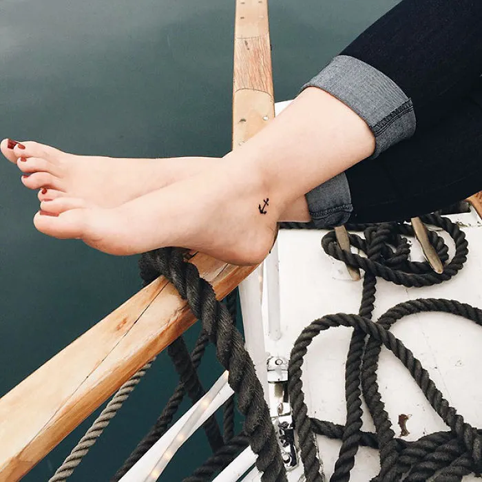 Small anchor foot tattoo on a boat, demonstrating less is more in minimalist tattoo design.