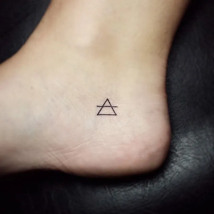 Minimalist small foot tattoo with triangle design showcasing elegant simplicity.