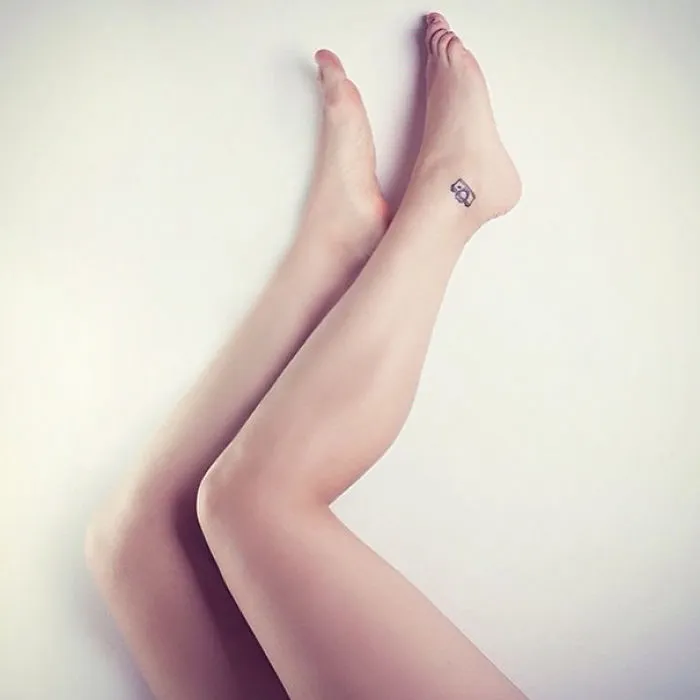 Minimalist small foot tattoo design on woman's ankle, showcasing "less is more" concept.