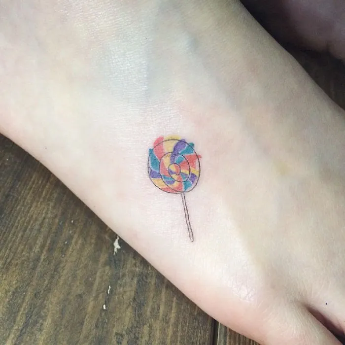 Colorful lollipop small foot tattoo, showcasing minimalist design.