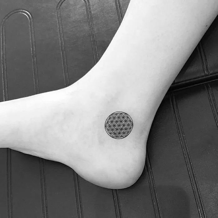 Minimalist small foot tattoo with geometric design illustrating "less is more" concept.