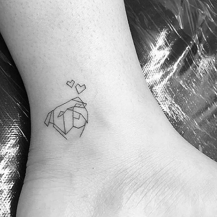 Minimalist small foot tattoo with geometric design and two tiny hearts, emphasizing the concept that less is more.