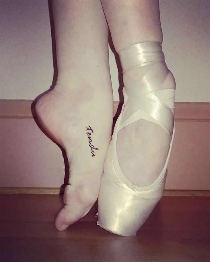 Ballet dancer with small foot tattoo on arch, showcasing minimalist tattoo idea.