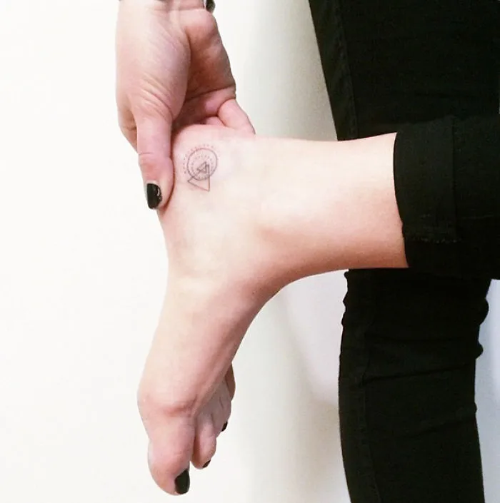 Minimalist small foot tattoo with geometric design, highlighting the essence of less is more in tattoo art.