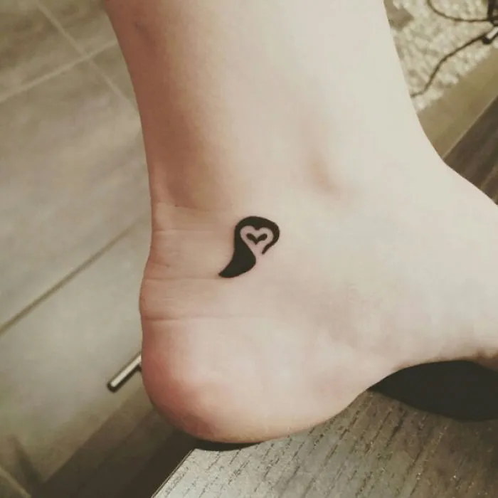 Minimalist small foot tattoo with heart design, emphasizing the concept that less is more in tattoo choices.